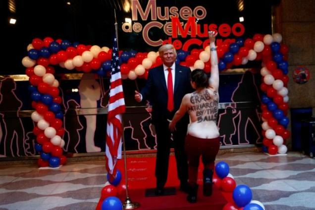 A topless FEMEN activist runs to grab the crotch of a life-sized wax statue of U.S. President-elect Trump during an unveiling ceremony at Madrid's wax museum